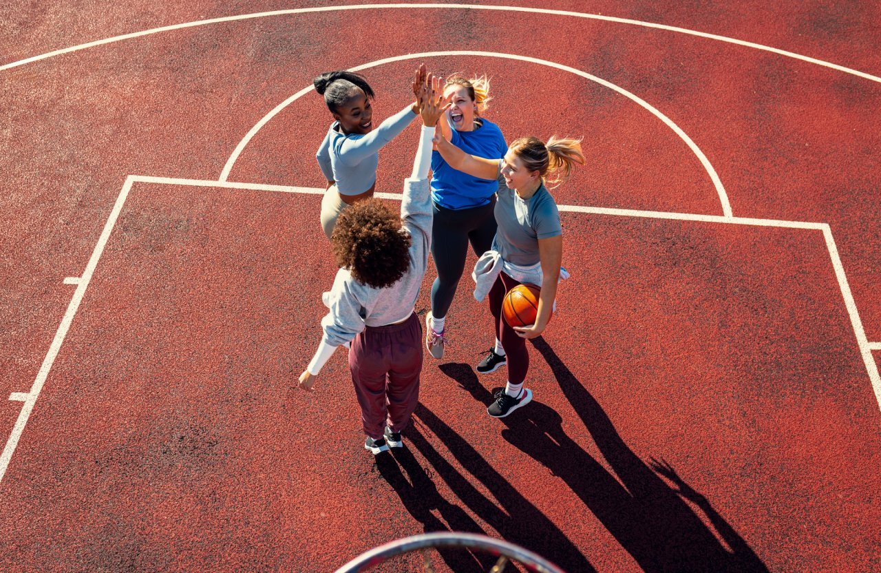 Diverse group of young woman having fun playing basketball outdoors.