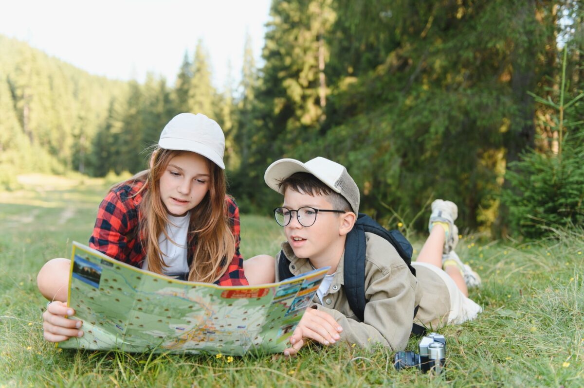 Tourists children hiking in forest reading map
